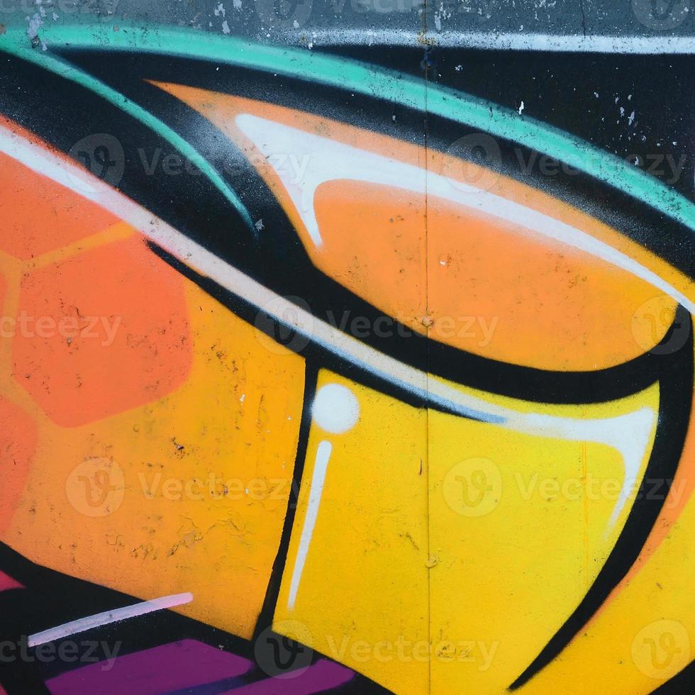 Fragment of graffiti drawings. The old wall decorated with paint stains in the style of street art culture. Colored background texture in warm tones photo