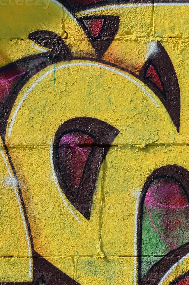 fragmento de dibujos de graffiti. la antigua muralla decorada con manchas de pintura al estilo de la cultura del arte callejero. textura de fondo coloreada en tonos cálidos foto