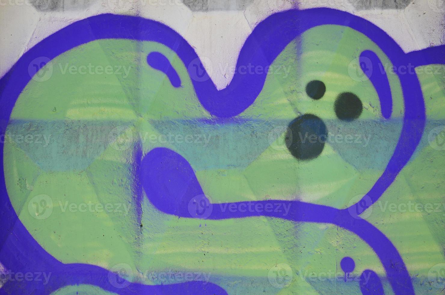 Fragment of an old colored graffiti drawing on the wall. Background image as an illustration of street art, vandalism and wall painting with aerosol paint photo