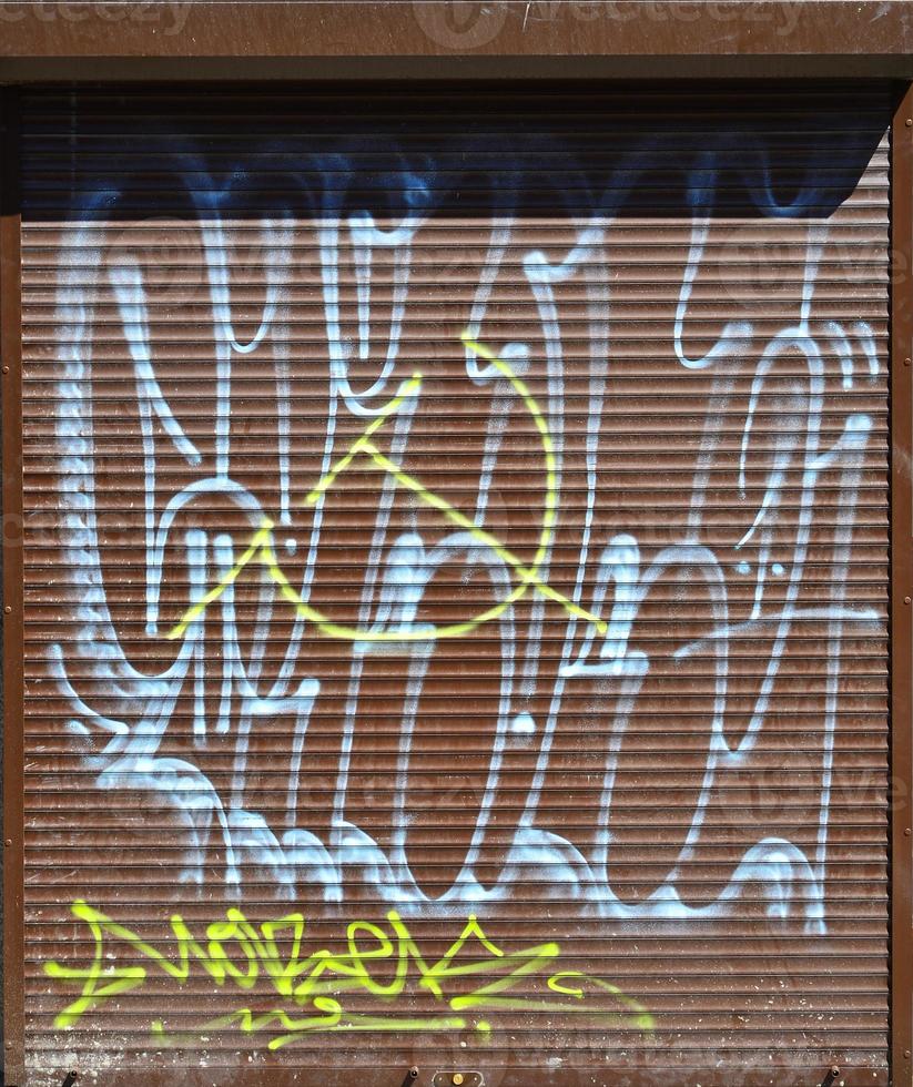 Fragment of an old colored graffiti drawing on the shutter door. Background image as an illustration of street art, vandalism and wall painting with aerosol paint photo