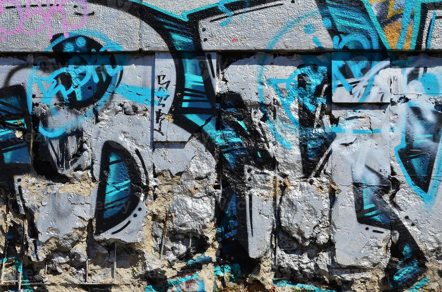 Fragment of an old colored graffiti drawing on the wall. Background image as an illustration of street art, vandalism and wall painting with aerosol paint photo