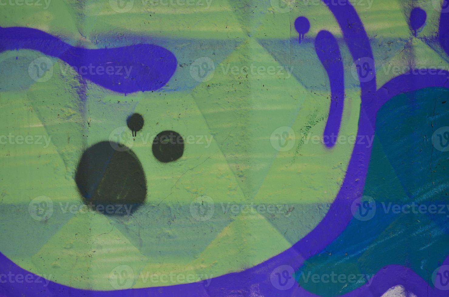Fragment of an old colored graffiti drawing on the wall. Background image as an illustration of street art, vandalism and wall painting with aerosol paint photo