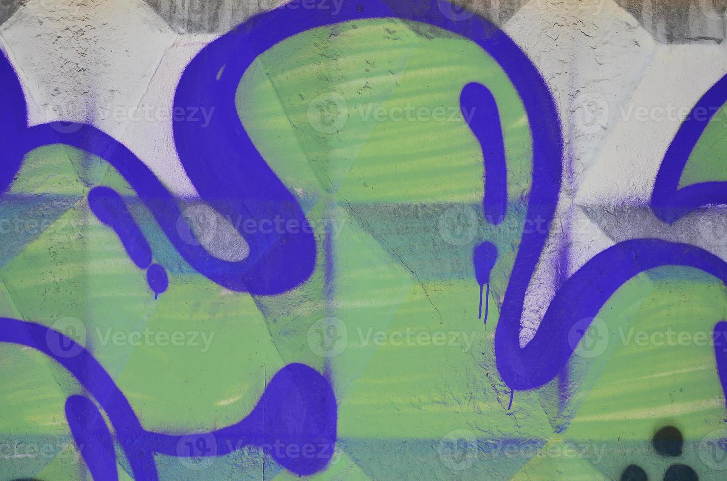 Fragment of an old colored graffiti drawing on the wall. Background image as an illustration of street art, vandalism and wall painting with aerosol paint photo