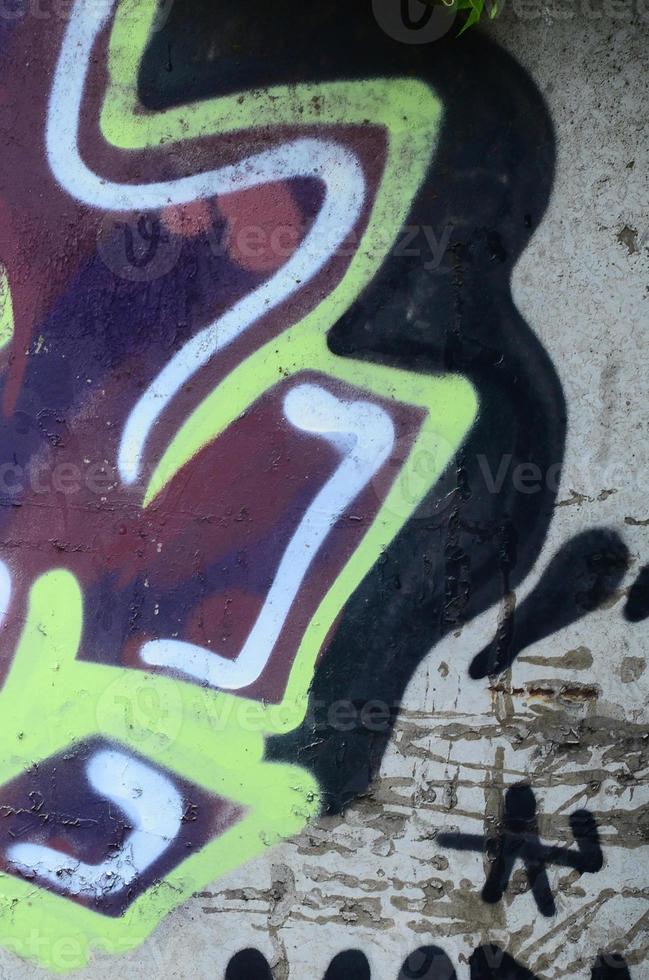 Fragment of graffiti drawings. The old wall decorated with paint stains in the style of street art culture. Colored background texture photo