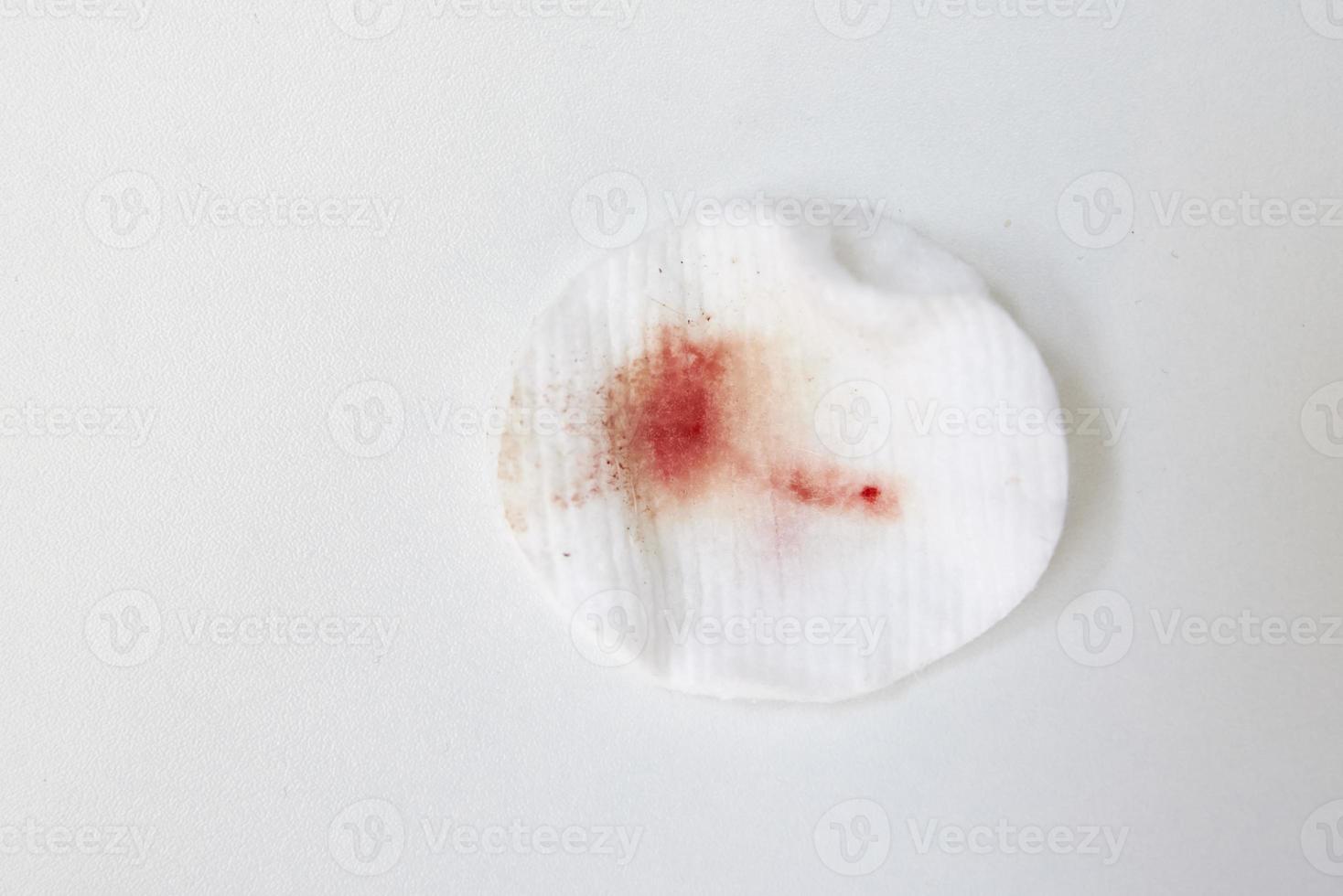 Cotton wool with blood stain on white background photo