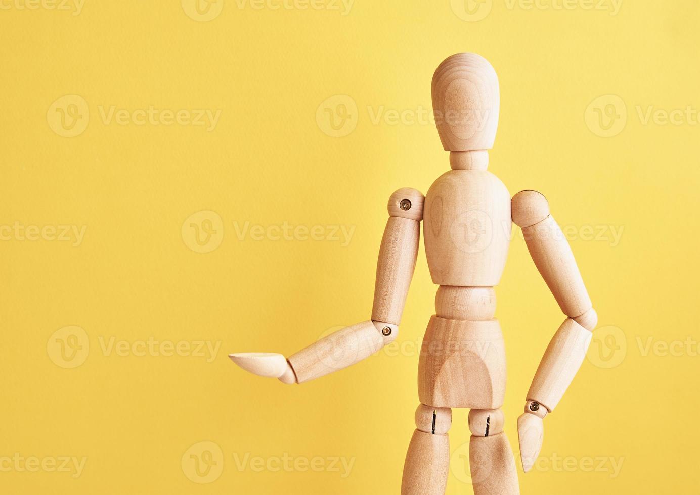 Wooden doll on yellow background photo