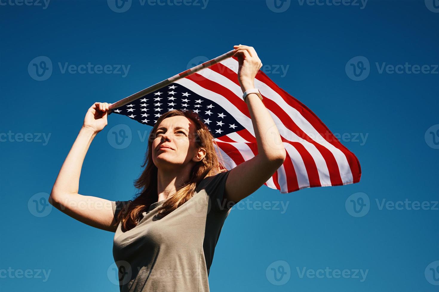 Woman holds usa flag against blue sky photo