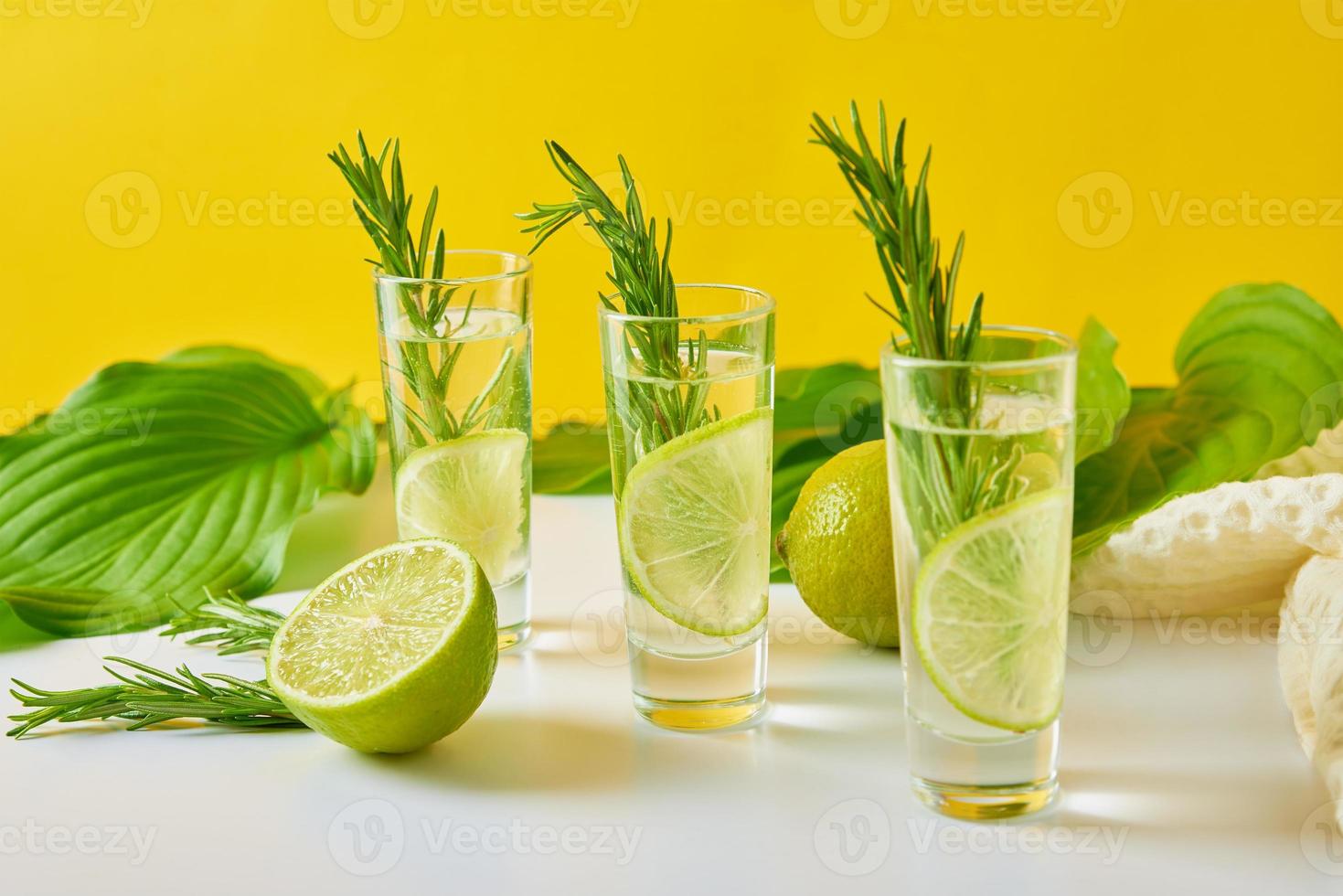 Drink with lime and rosemary on yellow background photo