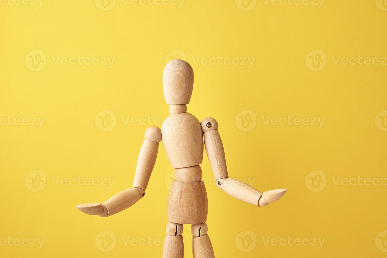 Wooden doll on yellow background photo