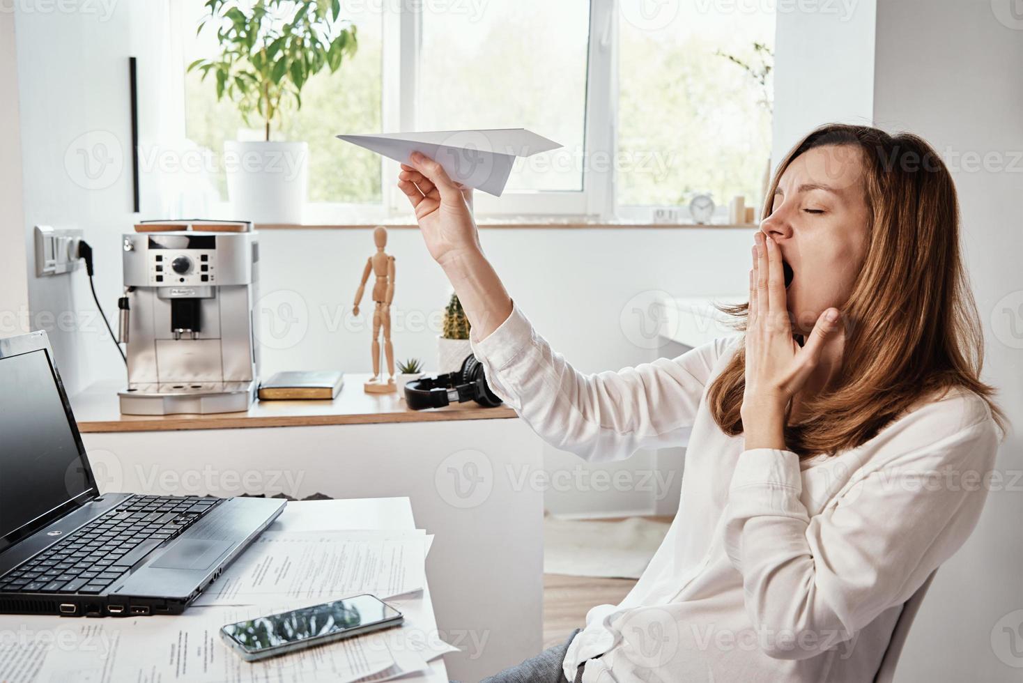 Woman plays with paper plain at home office. Procrastinate at remote work photo