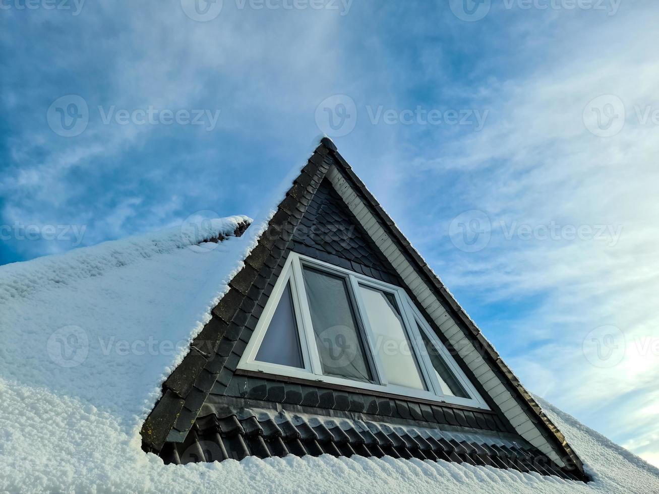 Open roof window in velux style with snow convered black roof tiles. photo