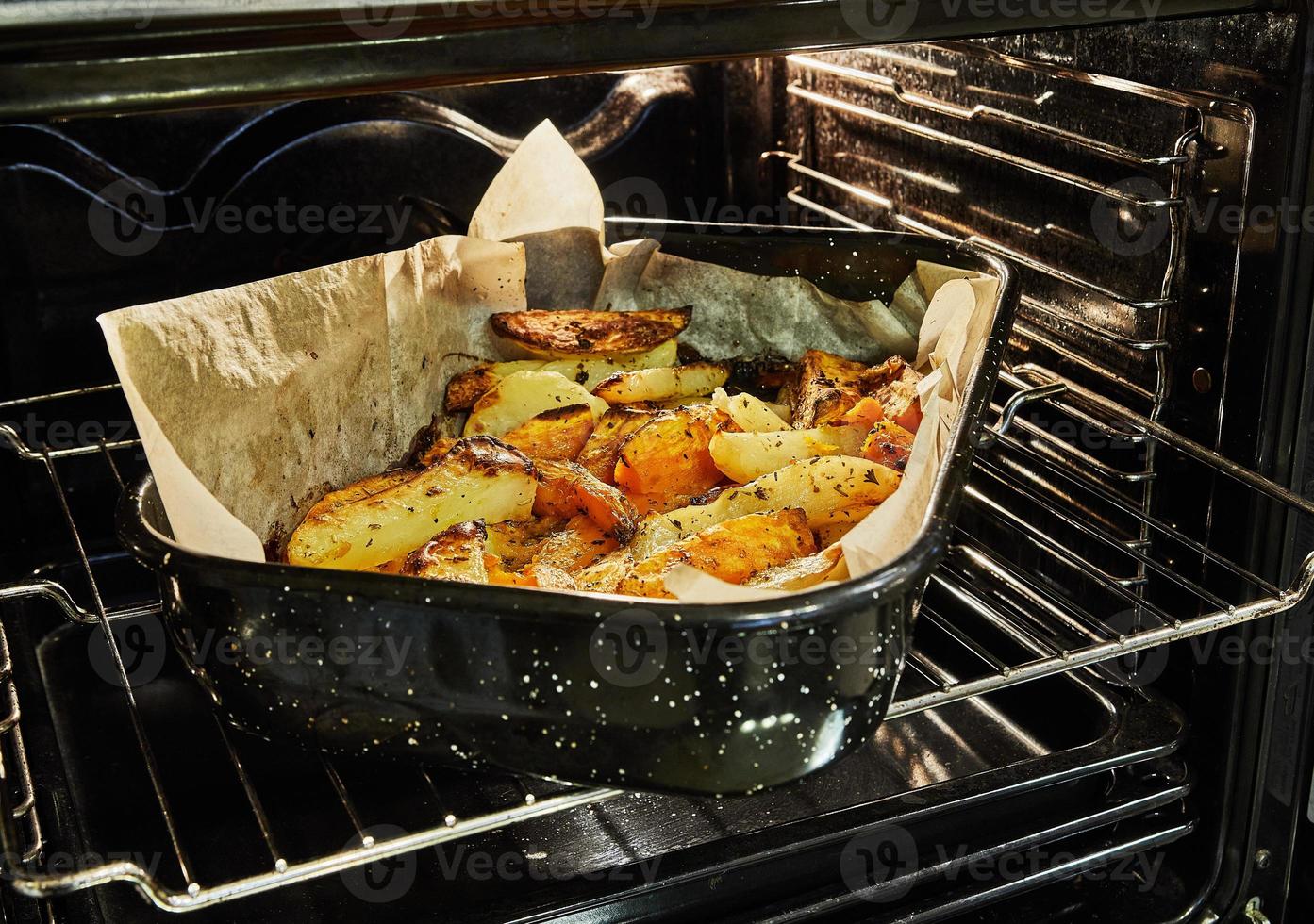 Potatoes with sweet potatoes are baked in the oven on baking sheet photo