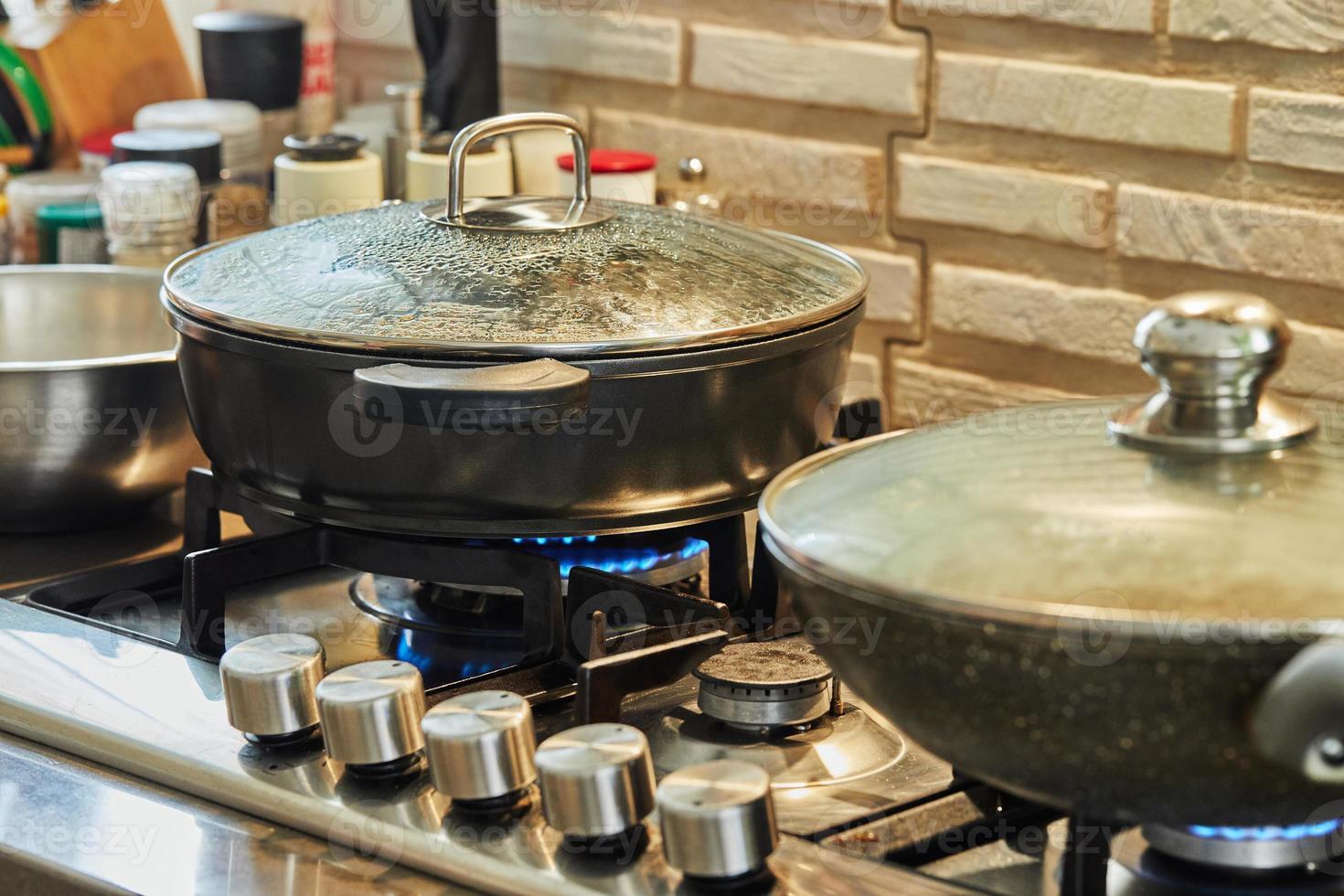 Preparing food in frying pan and casseroles on the gas stove in the kitchen. Home cooking concept photo