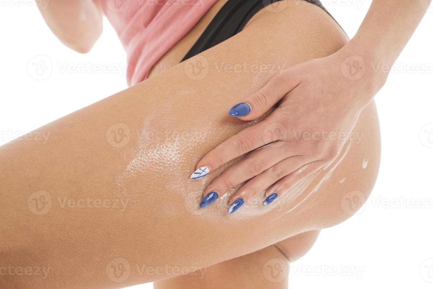 woman applies body lotion on her legs. isolated on white background photo