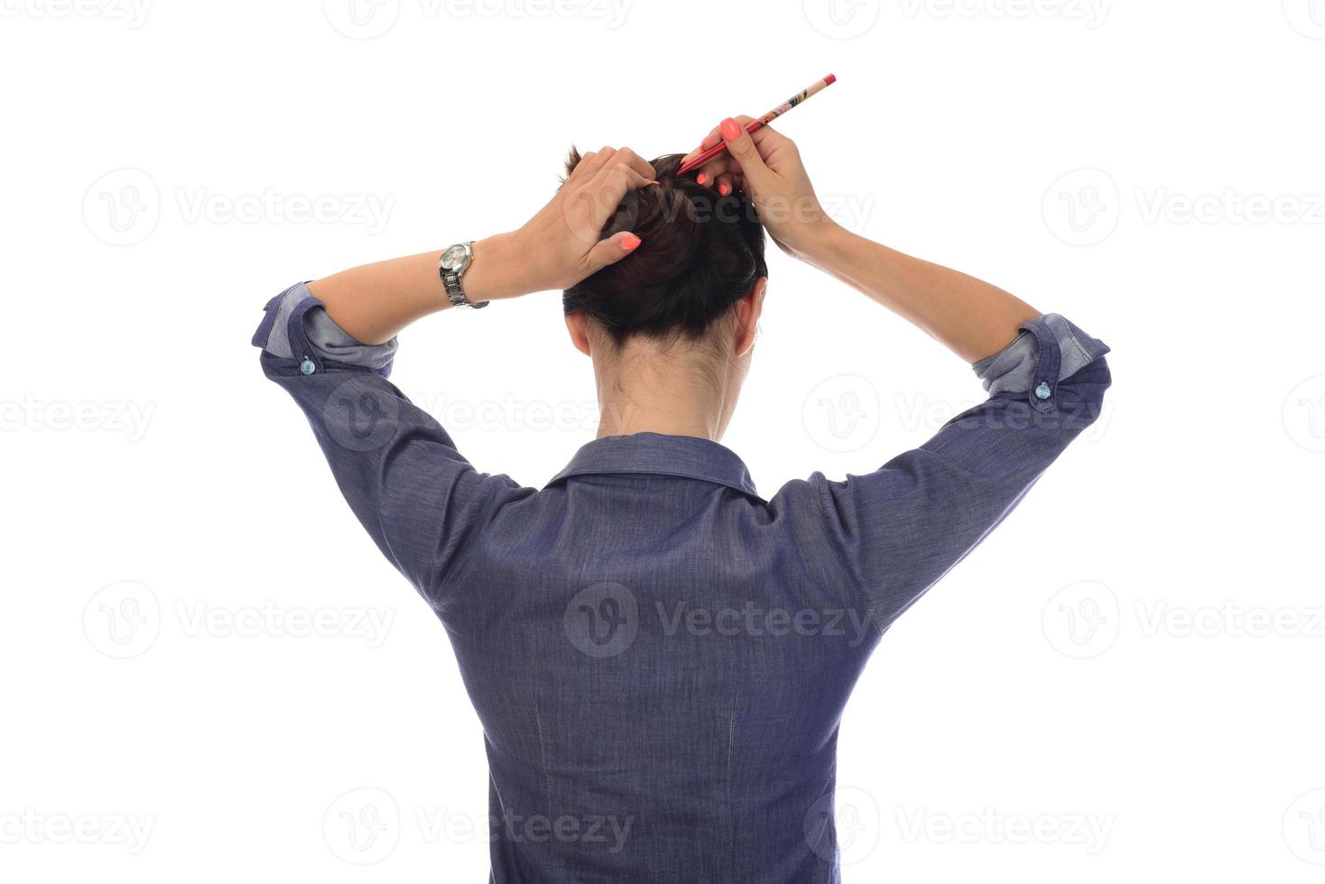 A woman makes a messy hair bun on her head photo