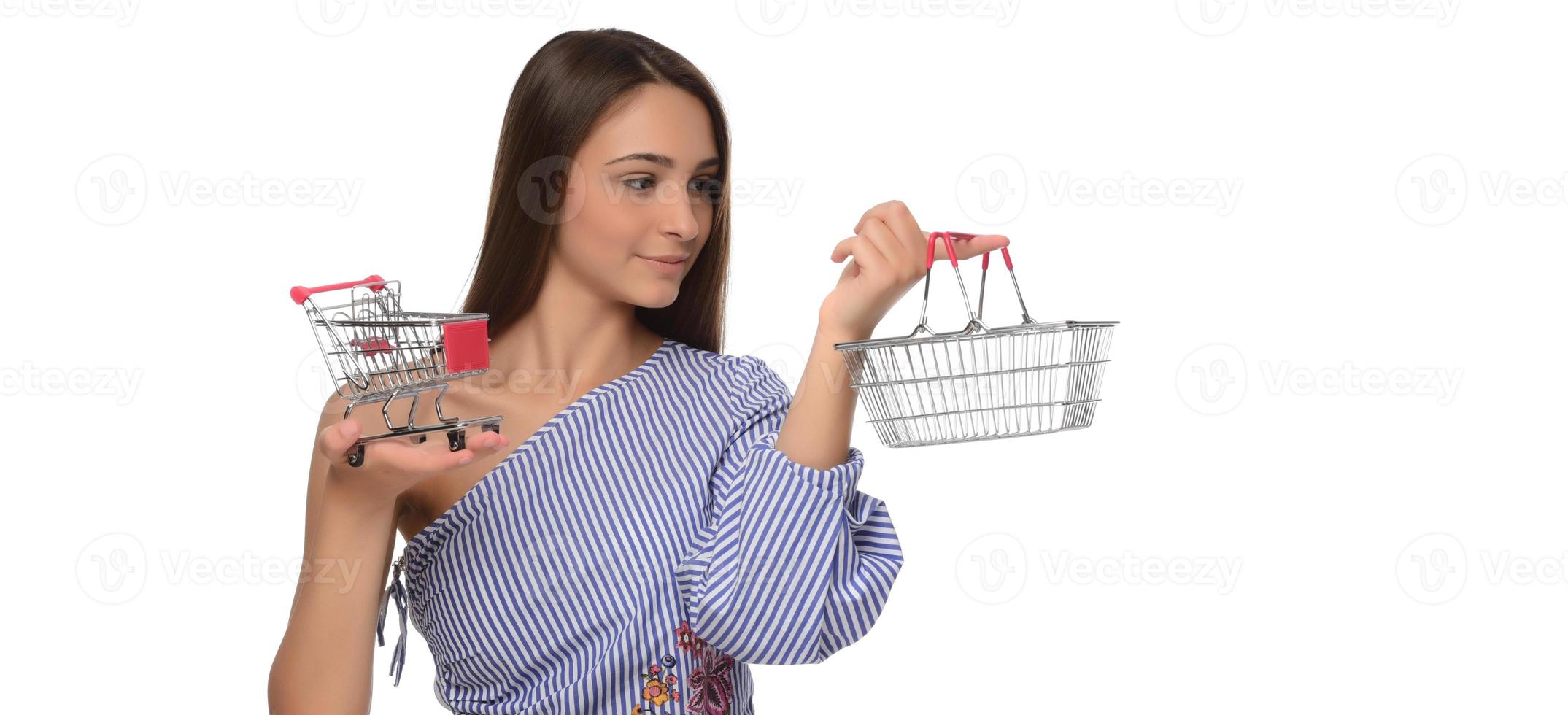 Woman thought about shopping. Girl is thinking about shopping. Woman chooses where to make purchase. Woman shopper with mini trolley from supermarket. photo