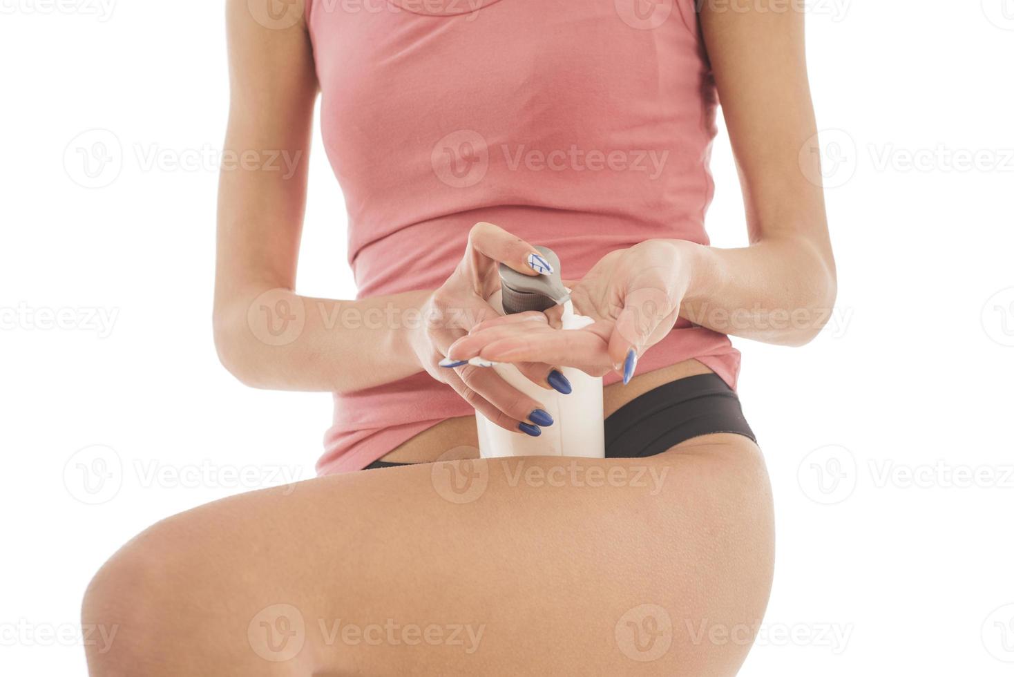 mujer aplica loción corporal en sus piernas. aislado sobre fondo blanco foto
