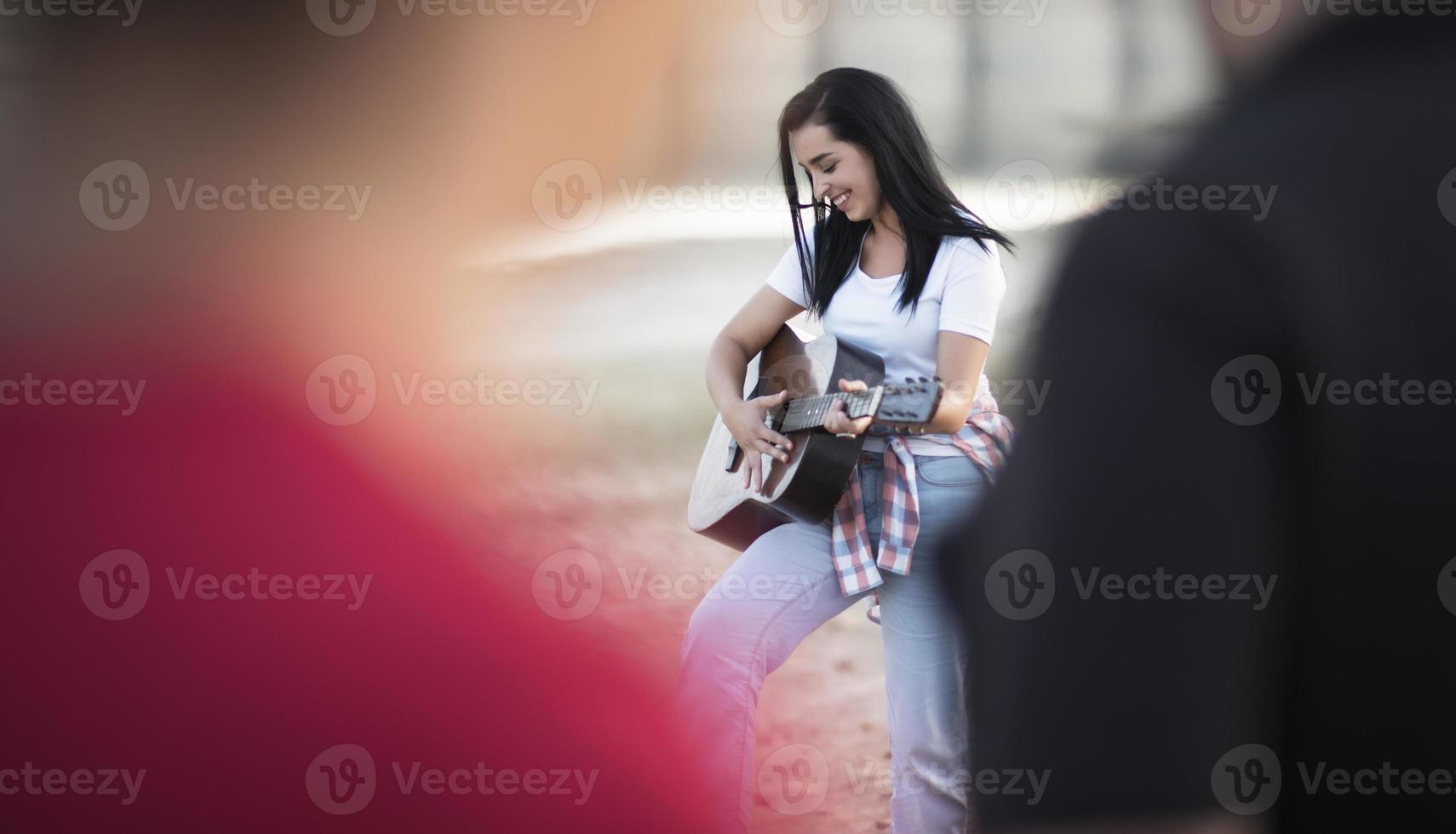 Portrait of a young woman playing guitar near bonfire by the lake photo