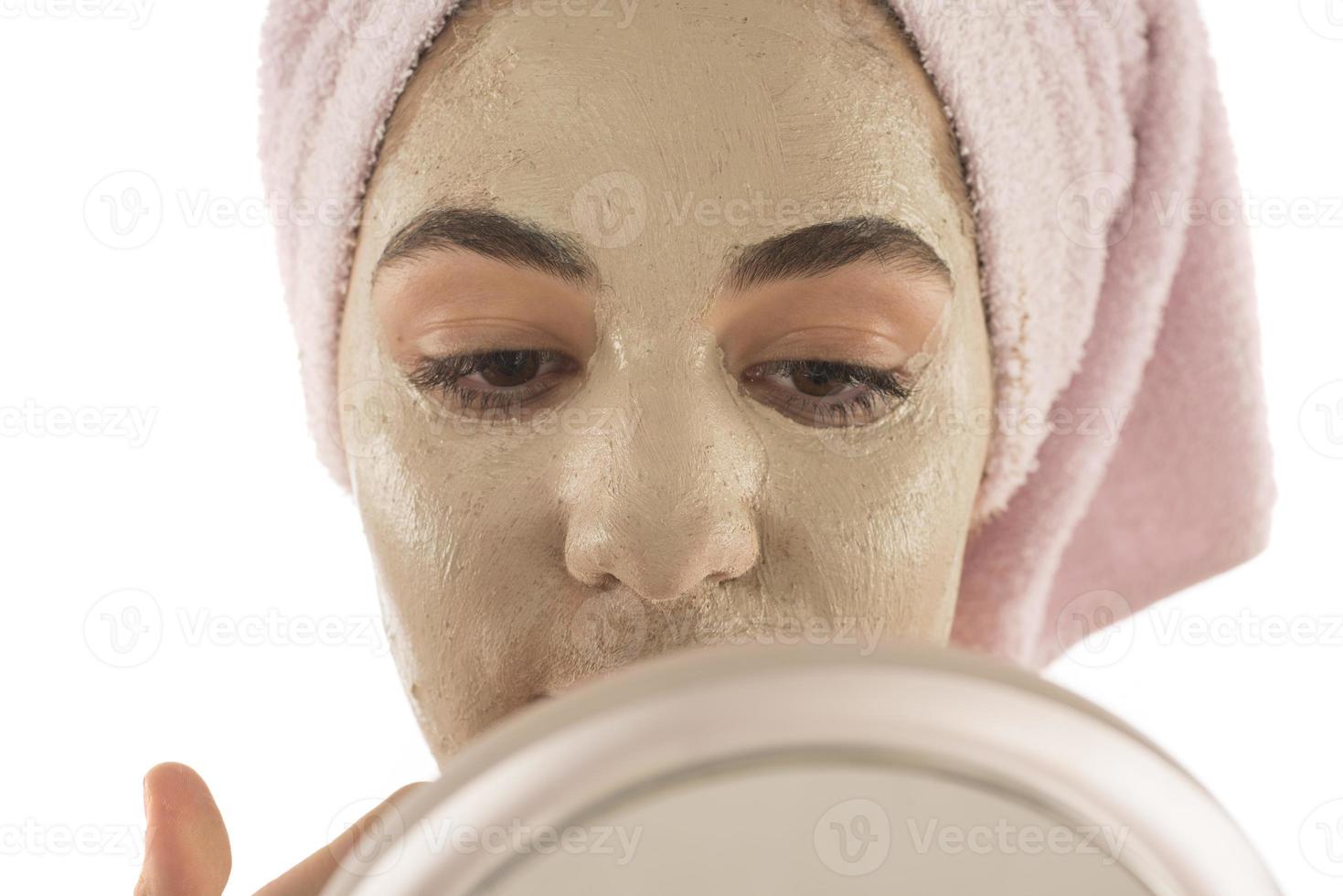 Beauty procedures skin care concept. Young woman applying facial mud clay mask to her face photo