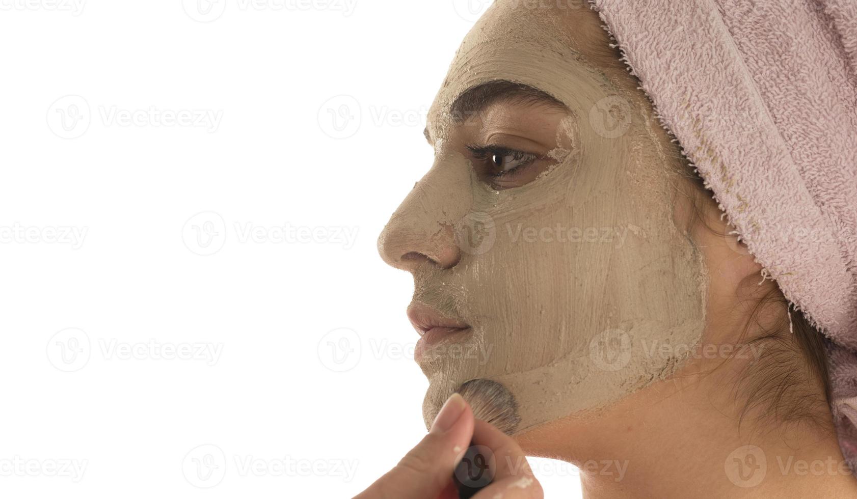 procedimientos de belleza concepto de cuidado de la piel. mujer joven aplicando máscara de arcilla de barro facial a su cara foto