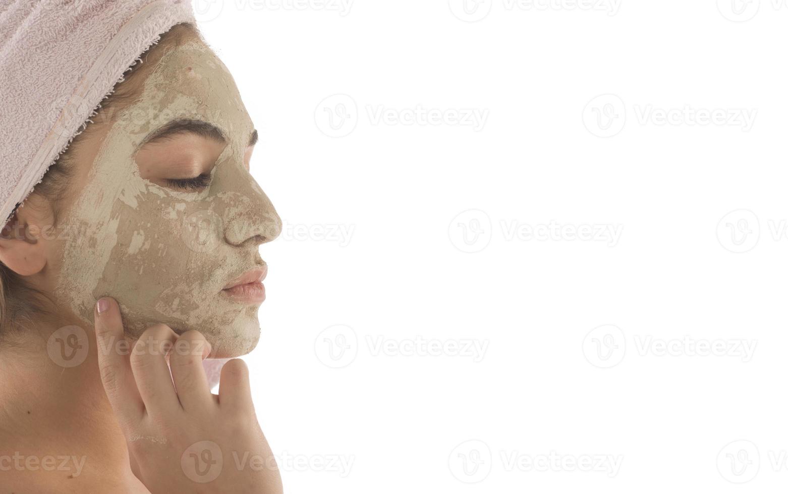 Beauty procedures skin care concept. Young woman applying facial mud clay mask to her face photo