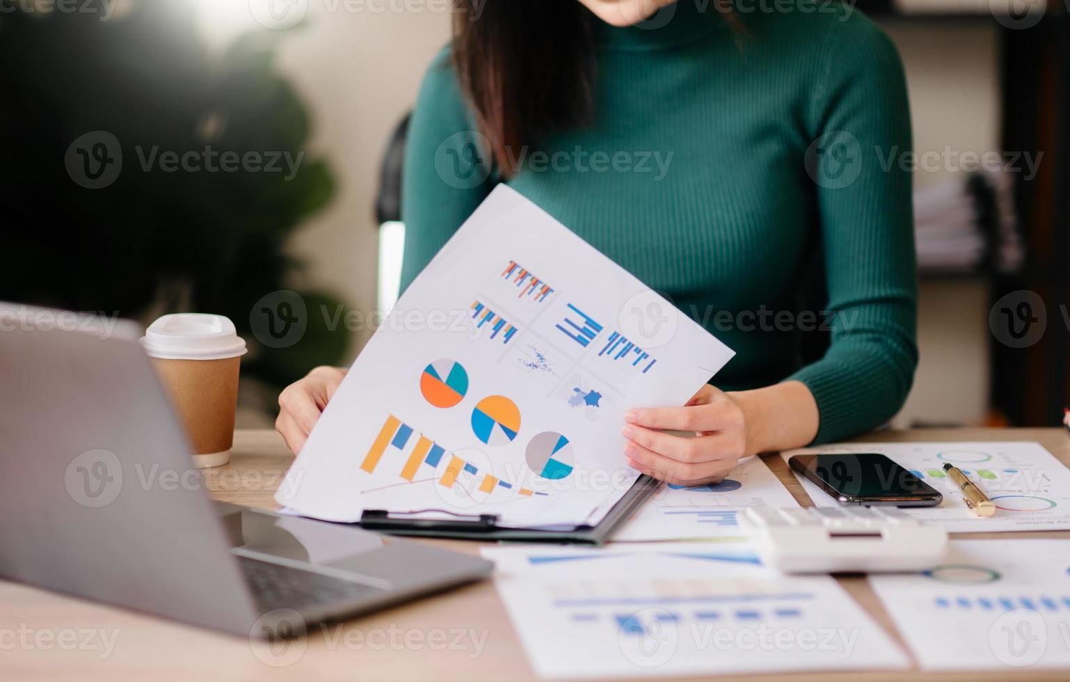 business documents on office table with smart phone and digital tablet and graph financial and woman working at office photo