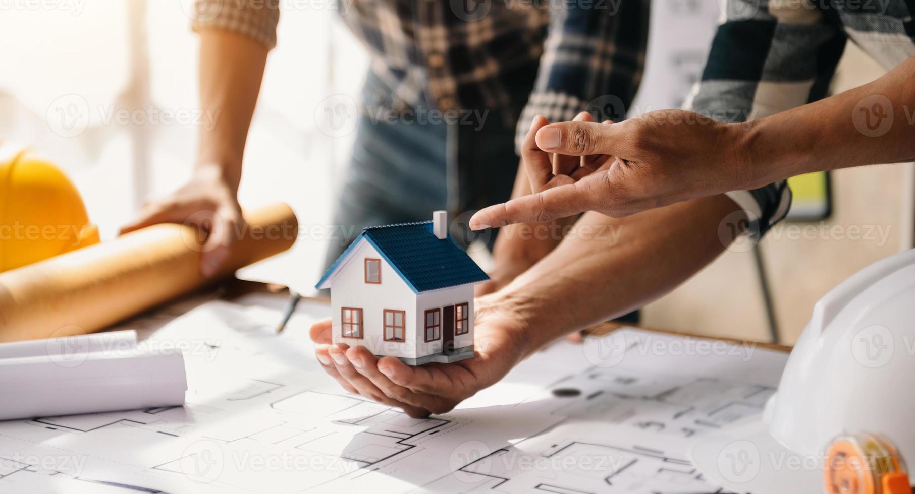 Scale model house on table with architects. Two architects making architectural model in office together. to form a new buildin photo