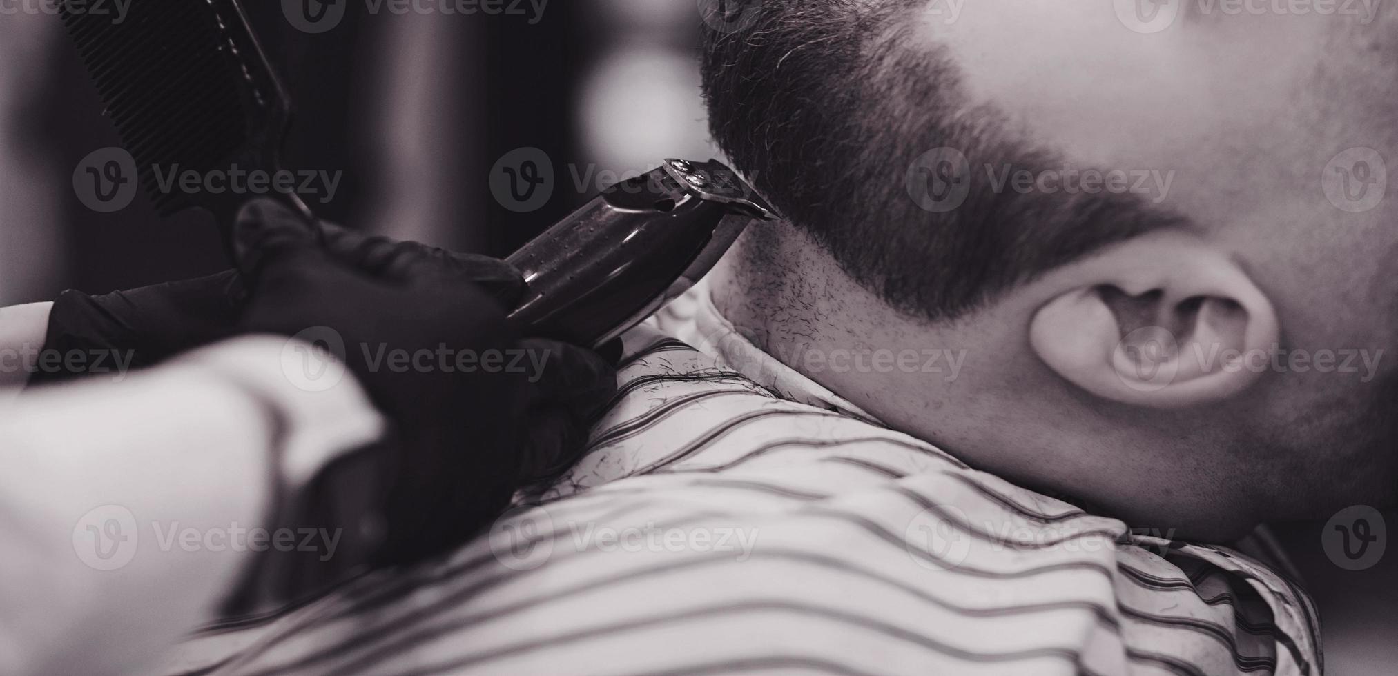 Barber cuts a man's beard photo