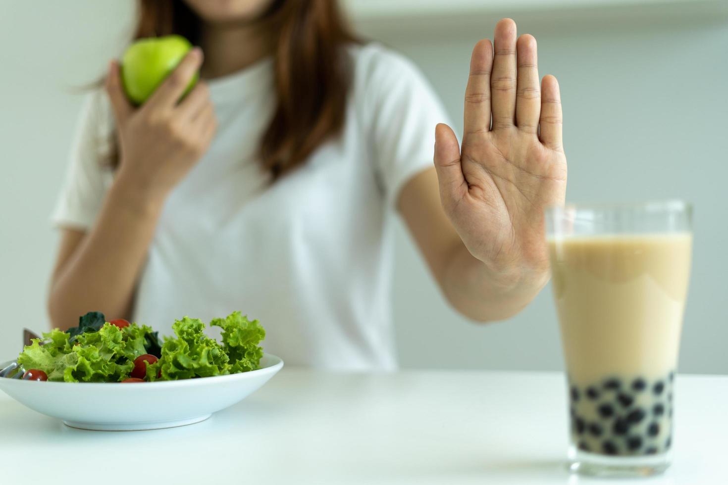 las mujeres rechazan la comida chatarra o los alimentos poco saludables como las donas y eligen alimentos saludables como las manzanas verdes y las ensaladas. concepto de ayuno y buena salud. foto