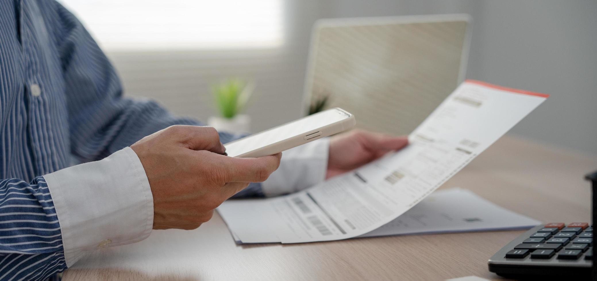 business man use phone to scan barcode or QR codes to pay credit card bill after receiving document invoice online. payment, receive, paying electricity, digital payments without money, technology photo