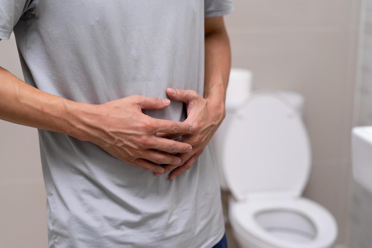 man standing has diarrhea and severely toxic food. Man touch belly in the bathroom. Abdominal pain, Diarrhea, Colon cancer concept photo