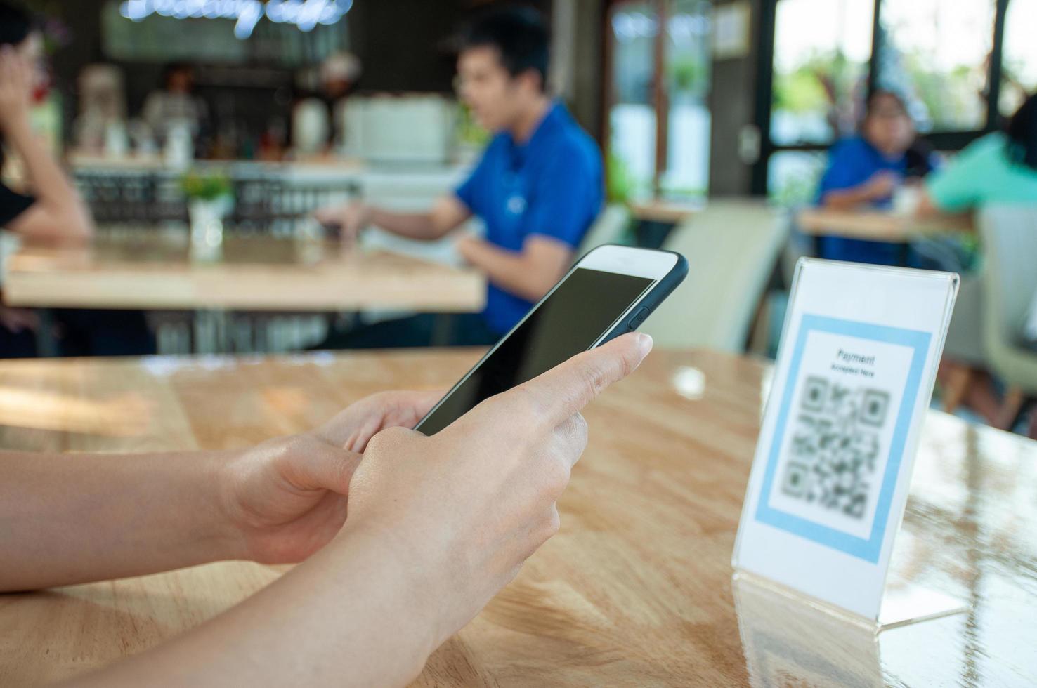 la mujer usa un teléfono inteligente para escanear el código qr para pagar en un café restaurante con un pago digital sin efectivo. elige menú y ordena acumula descuento. billetera electrónica, tecnología, pago en línea, tarjeta de crédito, aplicación bancaria foto