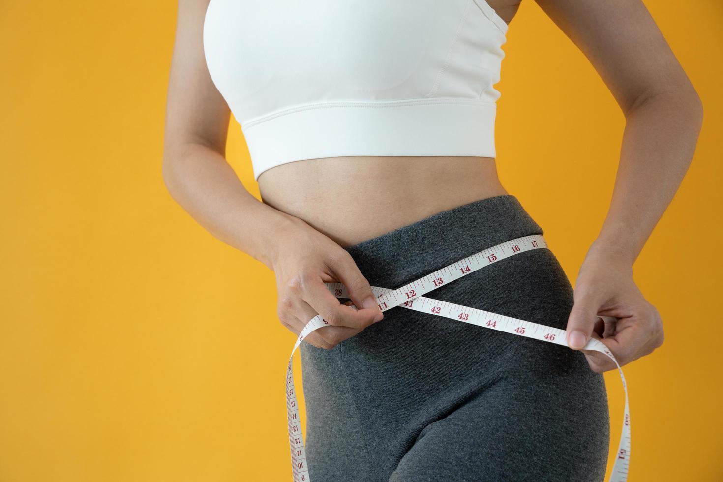 dieta y dieta. cinta métrica de uso de cuerpo femenino delgado de belleza. mujer con ropa de ejercicio logra el objetivo de pérdida de peso para una vida saludable, loca por la delgadez, cintura delgada, nutricionista. foto