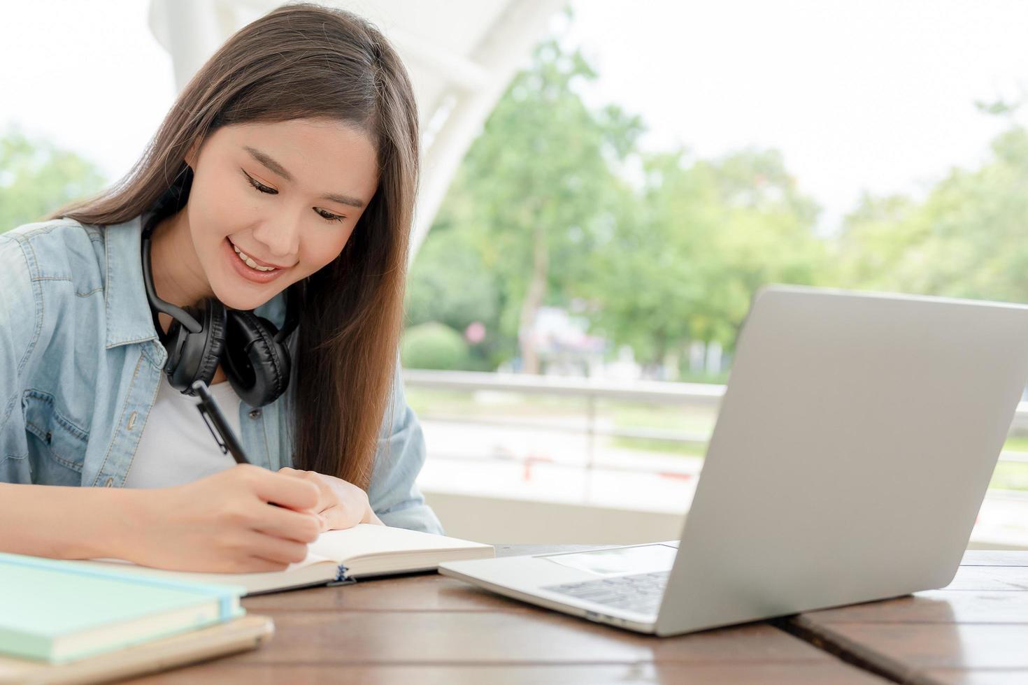 Beautiful Asian woman student excited check language test result on laptop. Smile girl happy study online. Portrait female on international Asia University. Education, school, book, college campus photo