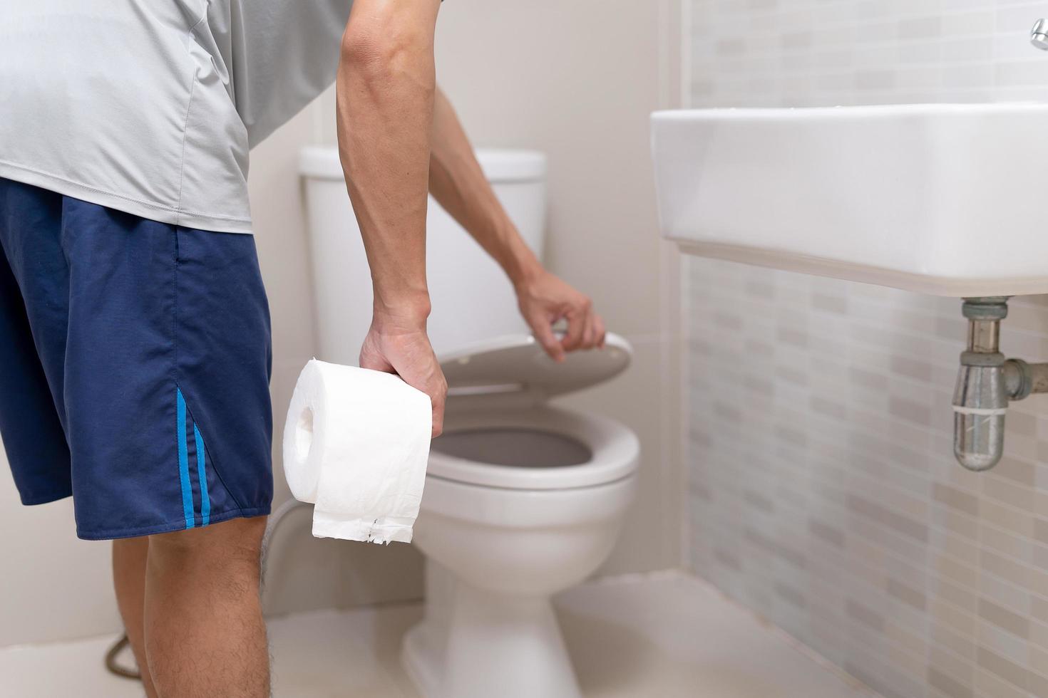 man standing has diarrhea and severely toxic food. Man touch belly in the bathroom. Abdominal pain, Diarrhea, Colon cancer concept photo