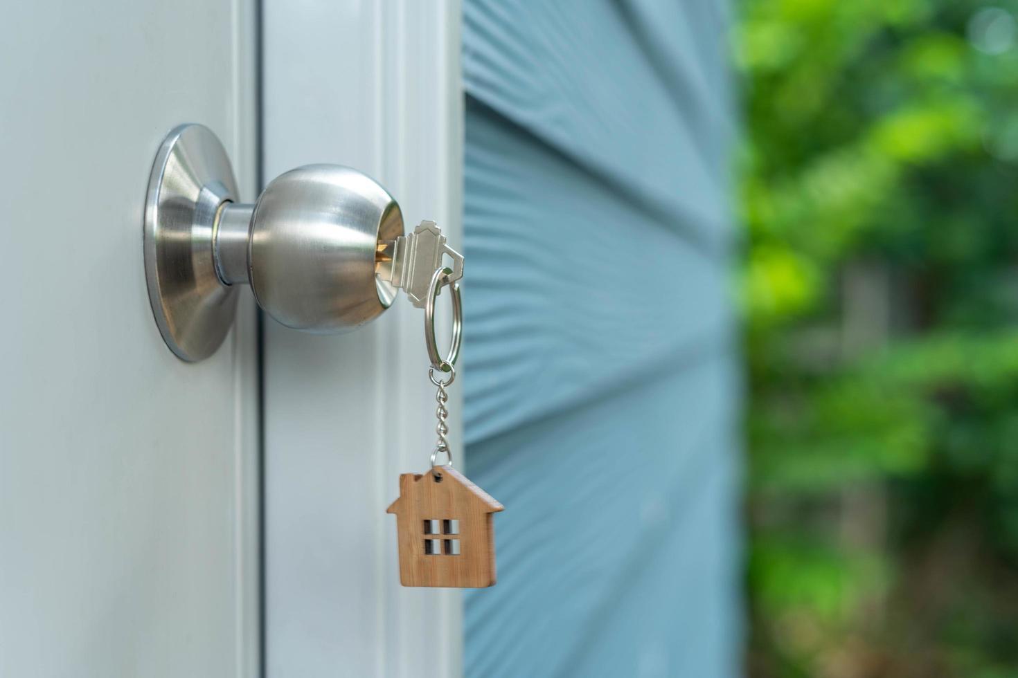 Landlord key for unlocking house is plugged into the door. Second hand house for rent and sale. keychain is blowing in the wind. mortgage for new home, buy, sell, renovate, investment, owner, estate photo