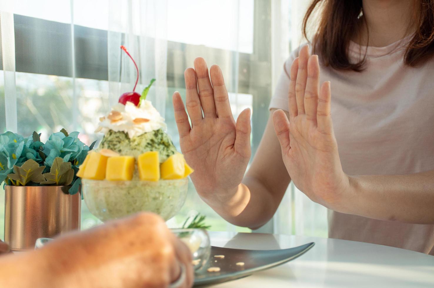 Woman pushes  bingsu cup  refuse to eat avoid  sugar and sweets for good health. Eating ideas. photo