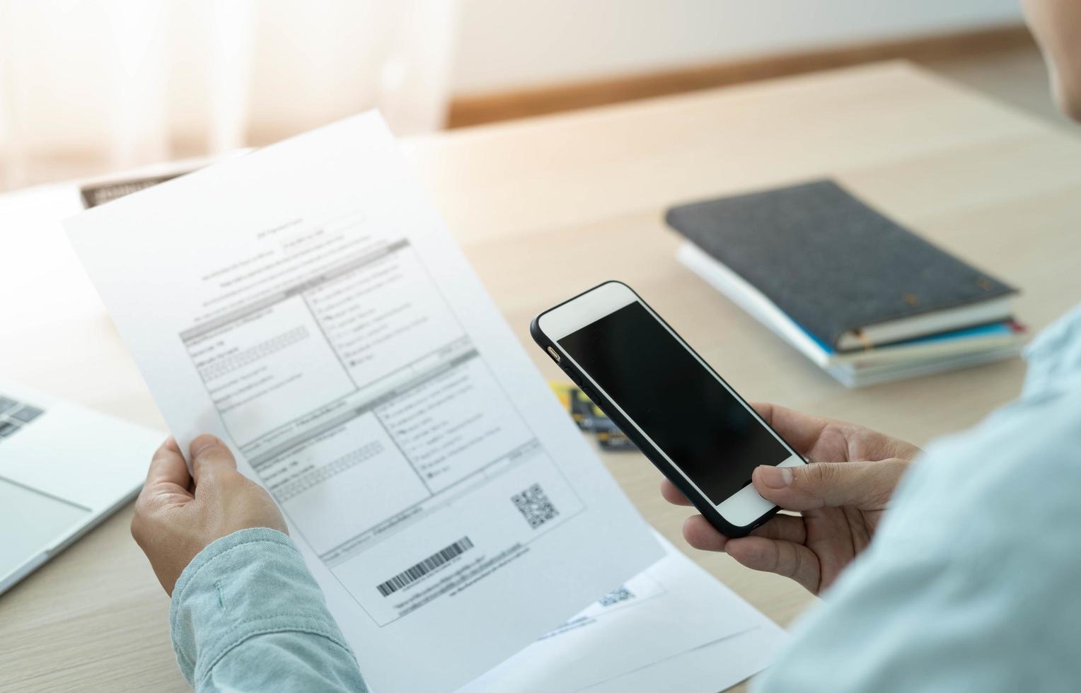 el hombre de negocios usa el teléfono para escanear códigos de barras o códigos qr para pagar la factura de la tarjeta de crédito después de recibir la factura del documento en línea. pago, recibir, pago de electricidad, pagos digitales sin dinero, tecnología foto