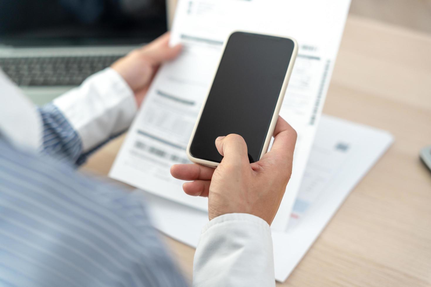 business man uses his phone to scan barcode or QR codes to pay his monthly credit card bill after receiving an invoice. online bill payment concept photo