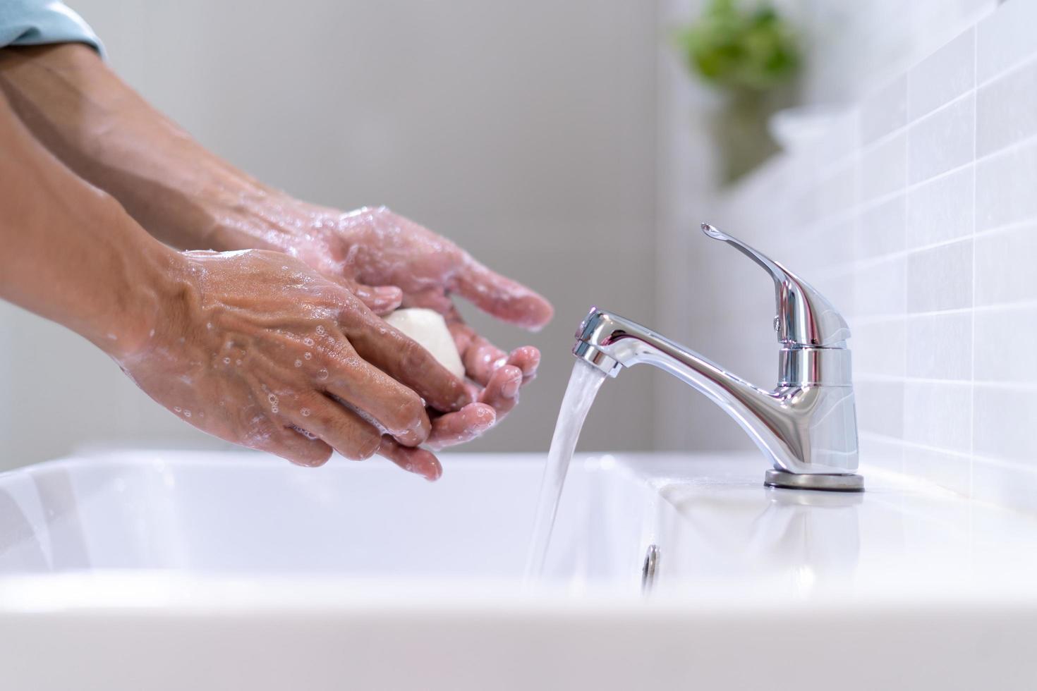 Men washing hands with soap and clean water in front of the bathroom sink to prevent the spread of germs. Washing hands with soap. photo