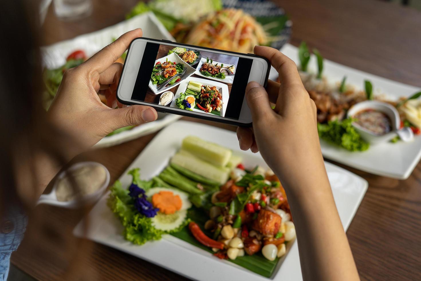 Woman take picture of a meal on the table after ordering food online to eat at home. Photography and use phone concepts photo