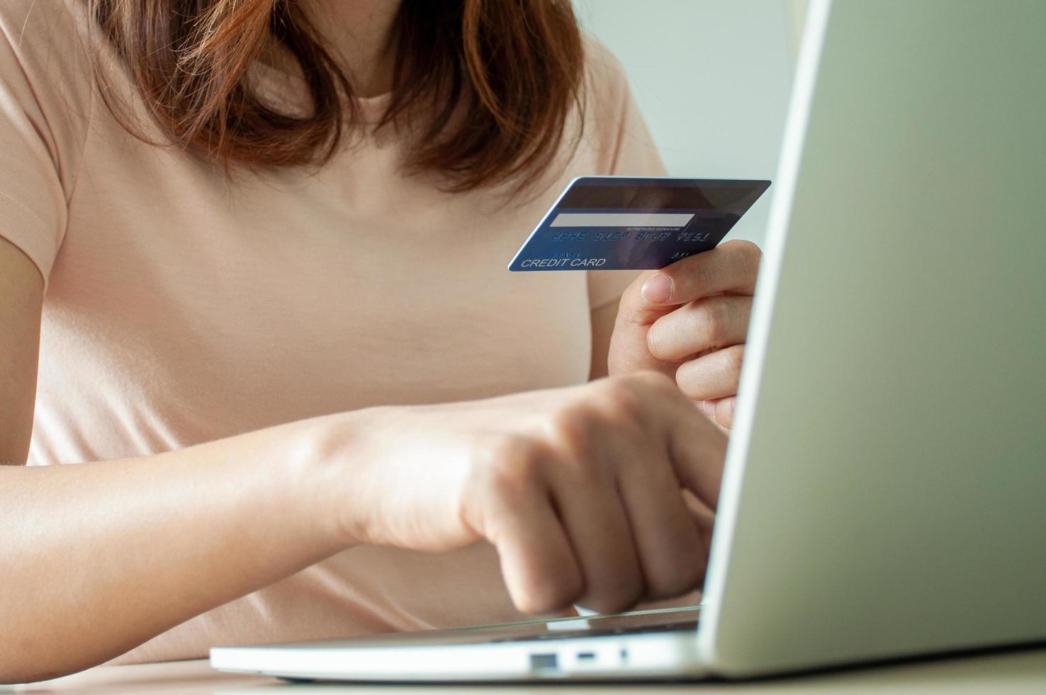 una mujer joven usa una tarjeta de crédito para comprar pagos en línea en una aplicación de computadora portátil o en un sitio web. concepto de comercio electrónico y compras en línea. quédate en casa y compra productos en línea. foto