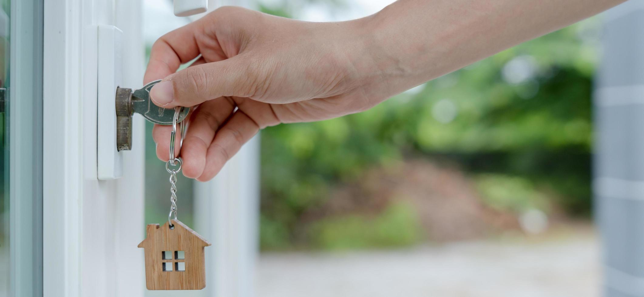 la llave de la casa del propietario para desbloquear una casa está enchufada en la puerta. casa de segunda mano en alquiler y venta. llavero está soplando en el viento. propietario de casa nueva, alquiler, venta, renovación, inversión. foto