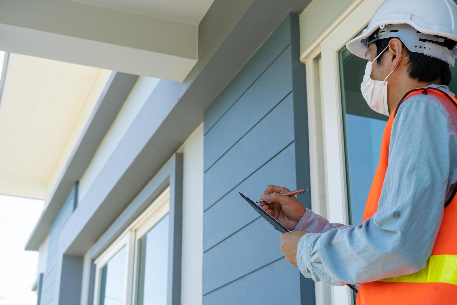 el inspector o ingeniero está revisando e inspeccionando el edificio o la casa usando una lista de verificación. ingenieros y arquitectos trabajan en la construcción de la casa antes de entregársela al propietario. foto