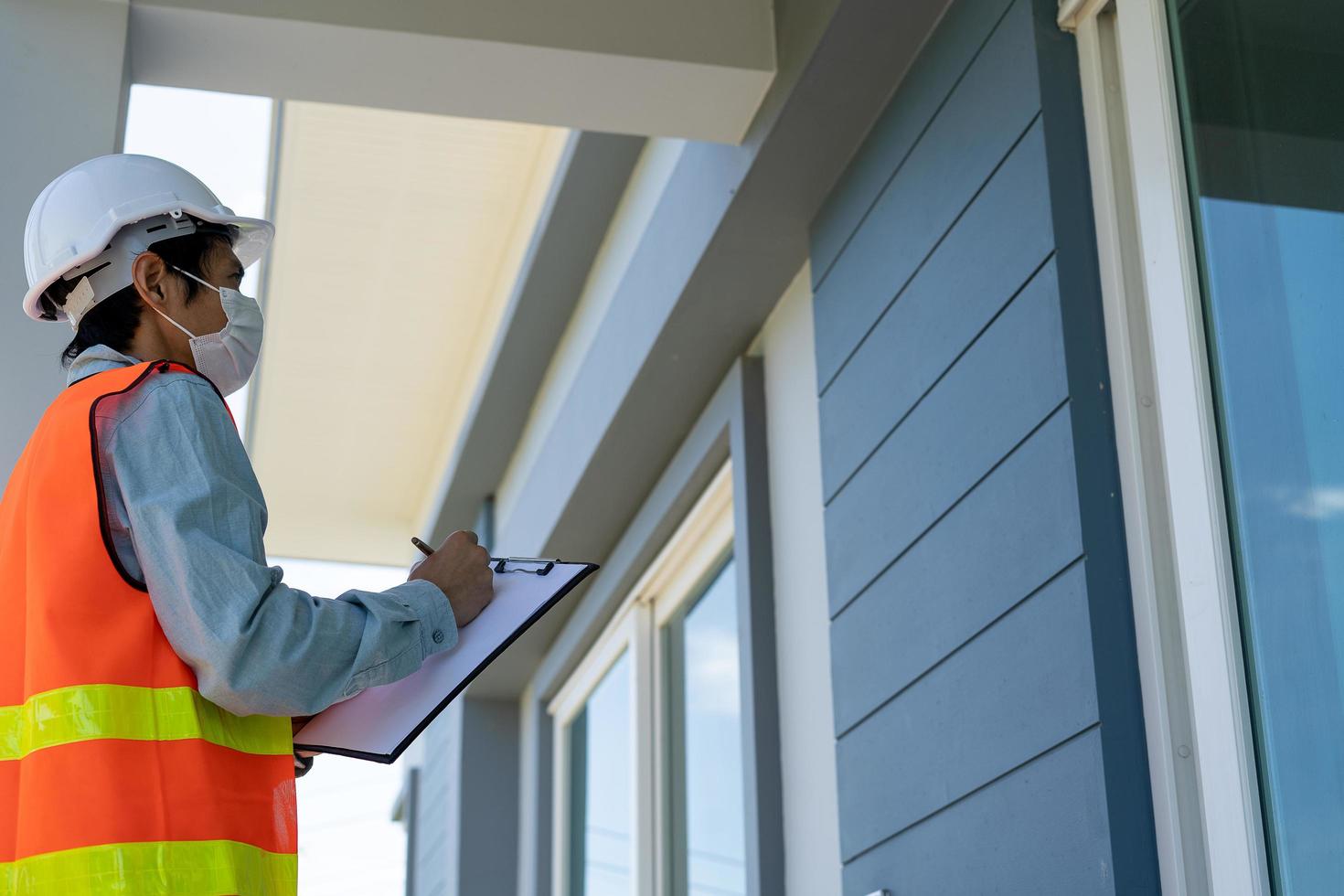 el inspector o ingeniero está revisando e inspeccionando el edificio o la casa usando una lista de verificación. ingenieros y arquitectos trabajan en la construcción de la casa antes de entregársela al propietario. foto