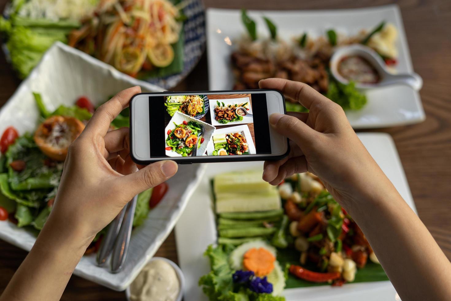 Woman take picture of a meal on the table after ordering food online to eat at home. Photography and use phone concepts photo