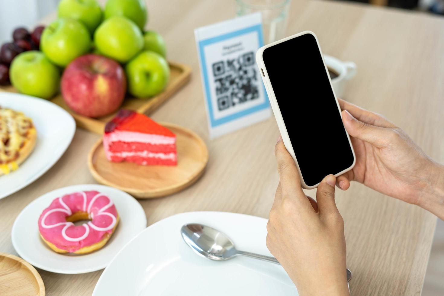 la mujer usa un teléfono inteligente para escanear el código qr para pagar en un café restaurante con un pago digital sin efectivo. elige menú y ordena acumula descuento. billetera electrónica, tecnología, pago en línea, tarjeta de crédito, aplicación bancaria foto