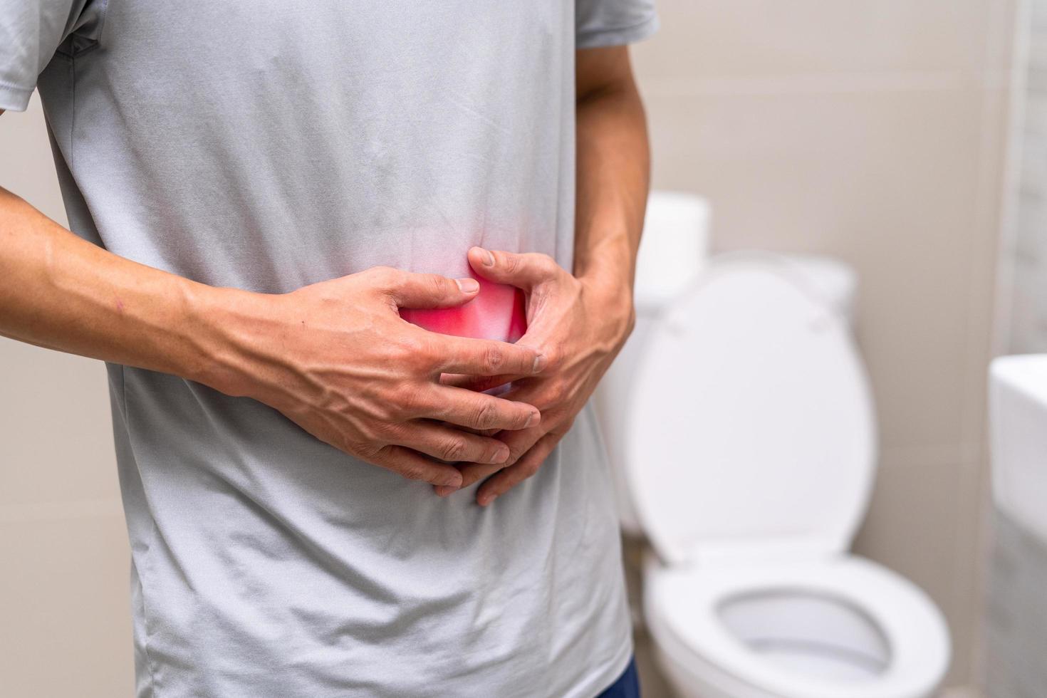 man standing has diarrhea and severely toxic food. Man touch belly in the bathroom. Abdominal pain, Diarrhea, Colon cancer concept photo