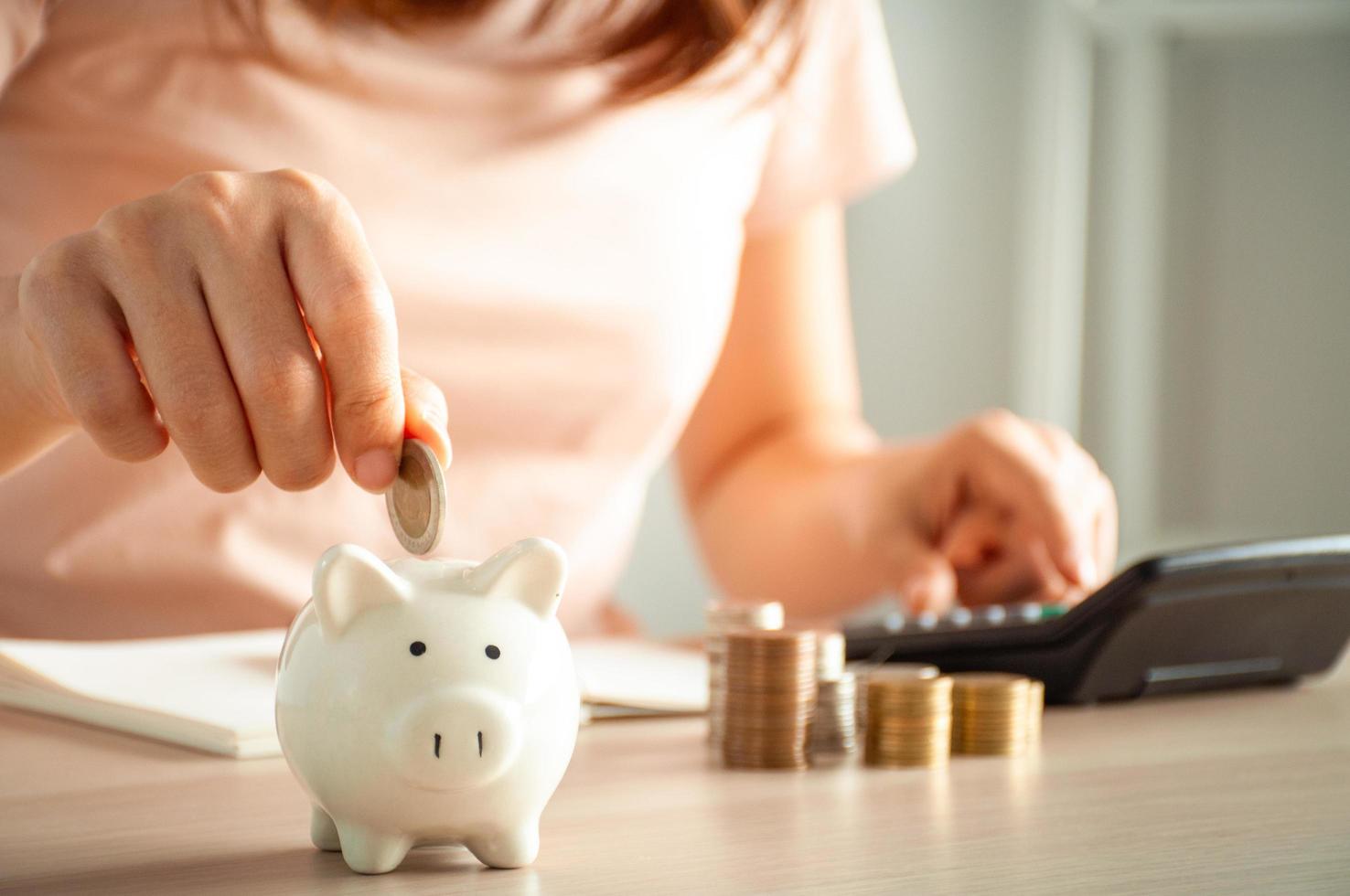Women are putting coins in a piggy bank for a business that grows for profit and saving money for the future. planning for retirement concept photo