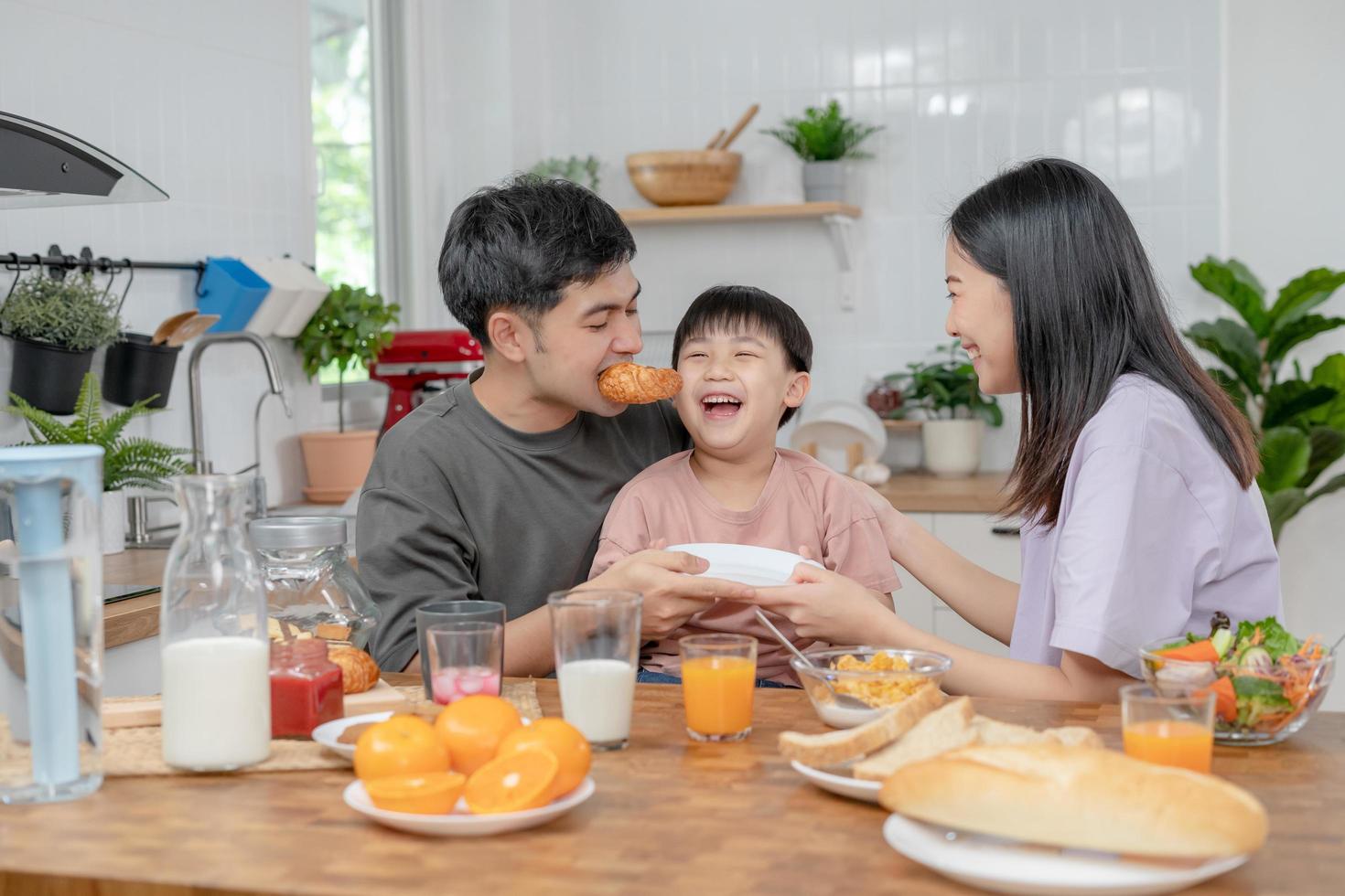 activities together during the holidays. Parents and children are having a meal together during the holidays. boy is teasing his father by giving him bread and vegetables. photo